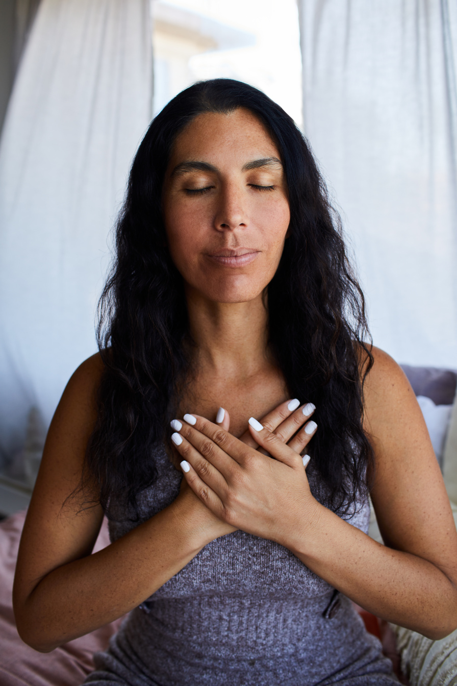 Woman with her hands clasped over her heart during meditation